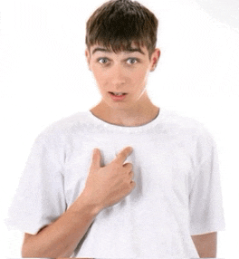 a young man in a white t-shirt is pointing at his chest