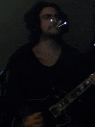 a man in a black shirt is playing an electric guitar