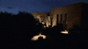 a house is lit up at night with a car parked in front of it