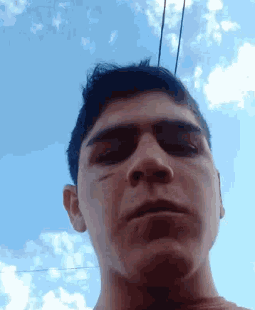 a close up of a man 's face in front of a blue sky