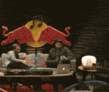 a man is sitting in front of a red bull statue