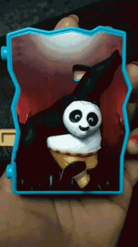 a person is holding a panda toy in a blue box