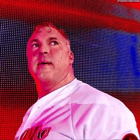 a man in a white shirt is standing in front of a large screen with a red and blue background .