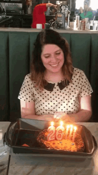 a woman in a polka dot shirt is smiling while lighting candles on a cake that says 2011