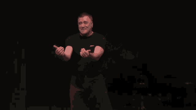 a man in a black shirt and black pants is standing with his hands on his hips .