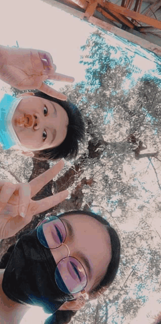 a boy and a girl wearing masks and sunglasses are giving a peace sign