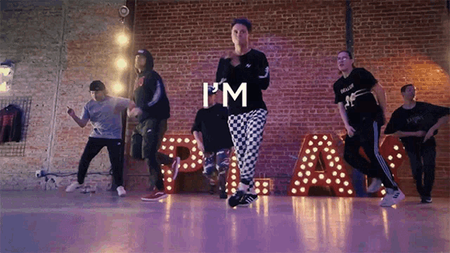 a group of people are dancing in front of a sign that says " i 'm "