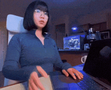 a woman wearing glasses is typing on a laptop computer