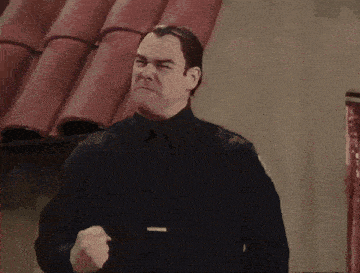 a man in a police uniform is making a funny face with his fist in the air