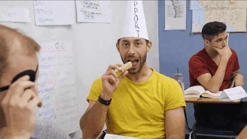 a man wearing a yellow shirt and a chef 's hat eating a snack