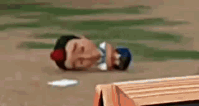 a cartoon character laying on the ground next to a car .