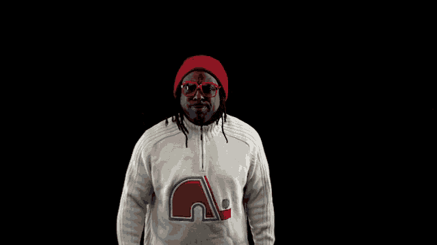 a man wearing a red hat and glasses is wearing a white sweater with the letter n on the front