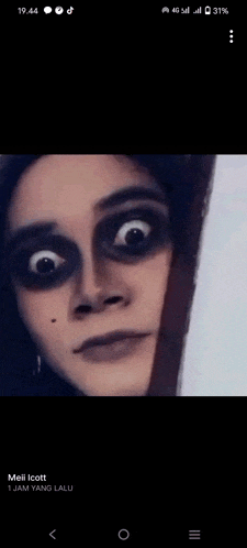 a woman with black makeup on her face is peeking out from behind a door