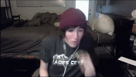 a young boy wearing a beanie and a t-shirt is sitting in front of a bed .