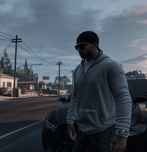 a man wearing sunglasses and a beanie walks down the street in front of a car