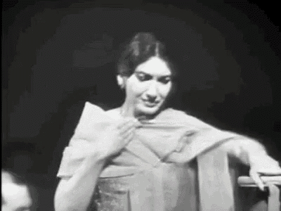 a black and white photo of a woman in a dress standing in front of a microphone .