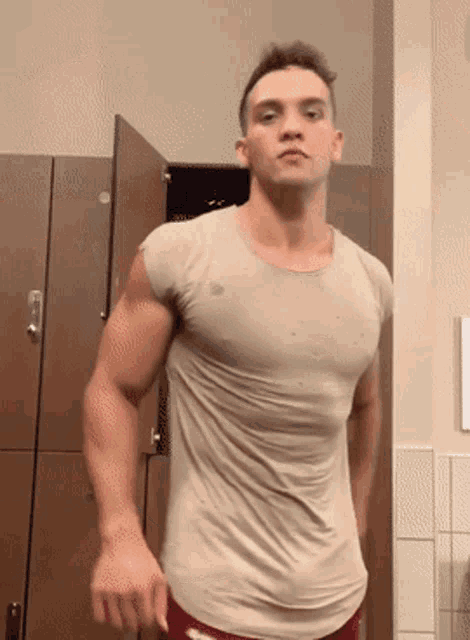 a man in a tan shirt is standing in front of a locker