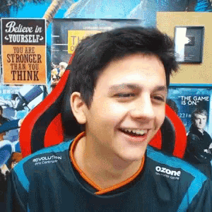 a young man is smiling in front of a believe in yourself sign