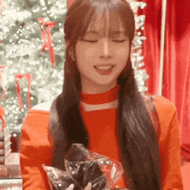 a woman in a red sweater is holding a bag of chocolate .