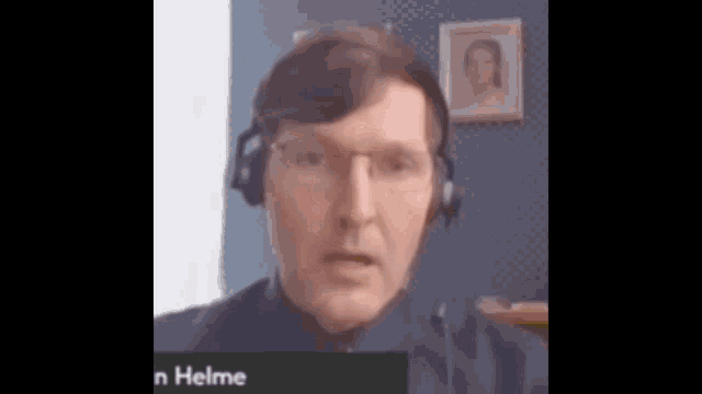 a man wearing glasses and headphones is on a video call with a name tag that says helmer