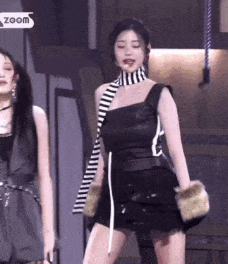 a woman wearing a black and white striped scarf and a black dress is dancing on a stage .