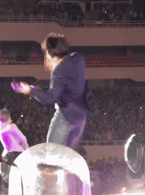 a man in a suit stands on a stage holding a purple object