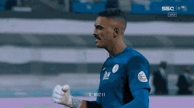 a soccer player wearing a blue shirt that says ' x_mh211 ' on the front