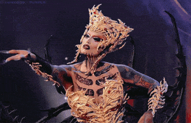 a woman in a gold costume with a crown on her head is on a twitter page