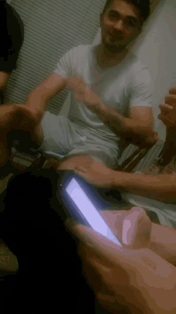 a group of people are sitting around a table with one man holding a cell phone