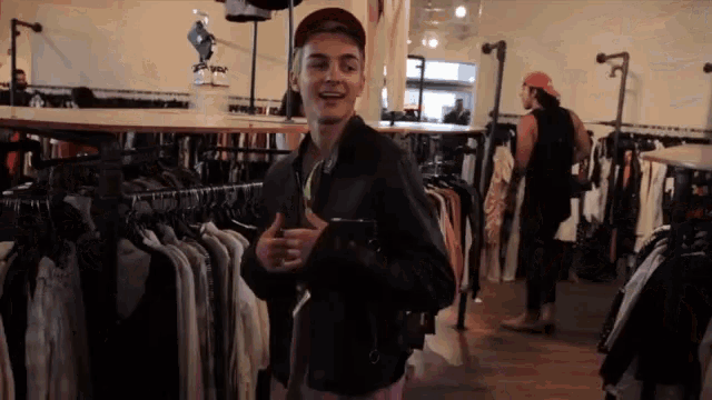 a man wearing a red hat and a black jacket stands in a clothing store