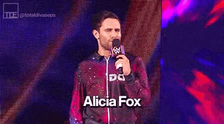 a man speaking into a microphone with the words oooox alicia foo written below him
