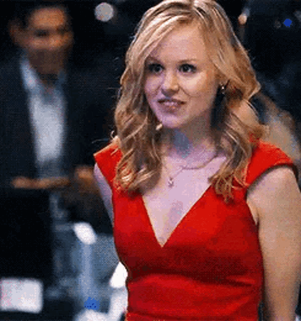 a woman in a red dress is standing in front of a man .
