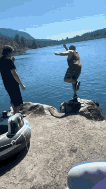 a man in a red tank top jumps into a body of water