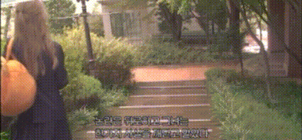 a woman is walking down a path in a park with chinese writing on the bottom