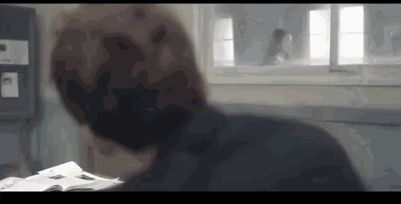 a man is standing in front of a window in a room looking out .