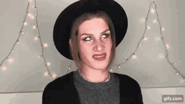 a woman wearing a black hat is making a funny face .