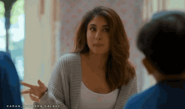 a woman in a gray sweater is talking to a boy in a blue shirt