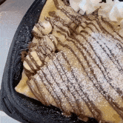 a chocolate crepe with whipped cream and powdered sugar