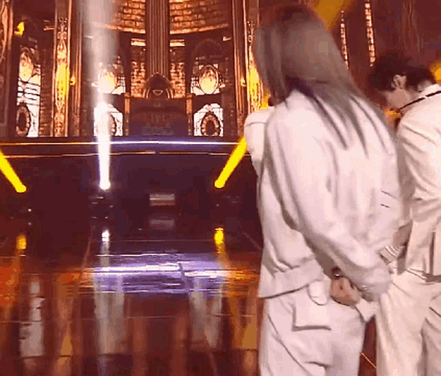 a man in a white suit is standing on a stage