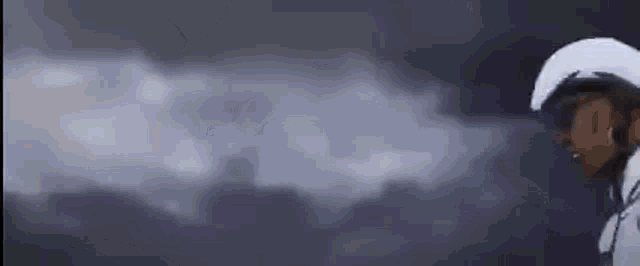 a person is standing in front of a cloudy sky with a smoke coming out of their mouth .