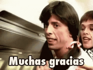 a man is holding a baby and says muchas gracias in spanish .