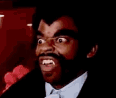 a man with a beard and fangs is making a funny face .