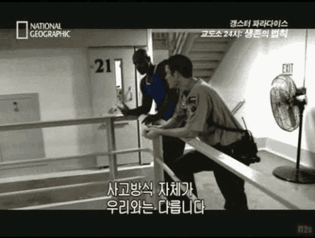 a man in a blue shirt is being escorted by two police officers in front of a door that has the number 21 on it