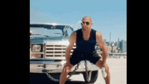 a man is squatting down in front of a car with chains around his legs
