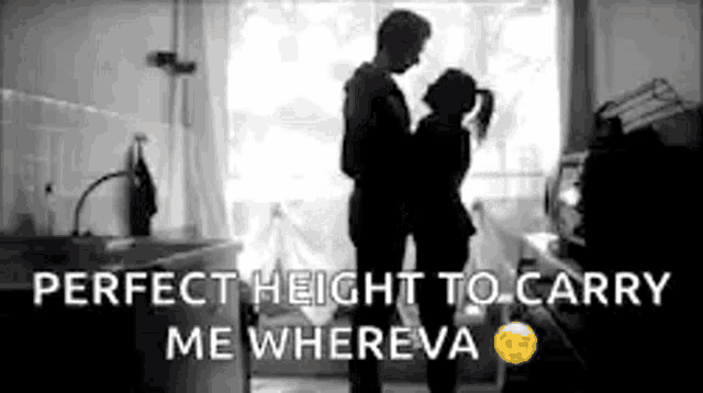 a man and a woman are hugging each other in front of a window in a kitchen .