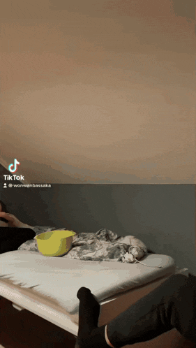 a tik tok video of a person laying on a bed with a bowl of food