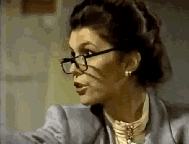a woman wearing glasses and earrings looks at something