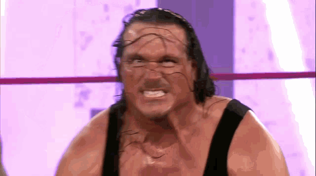 a wrestling wrestler is making a funny face in a ring .