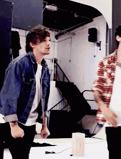 a man in a denim jacket is standing next to another man