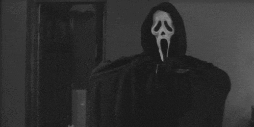a person wearing a scream mask is holding a knife in a black and white photo .